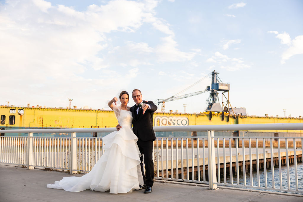 Bride and groom give a playful thumbs down in front of a cargo ship during their Hilton San Diego Bayfront wedding portraits
