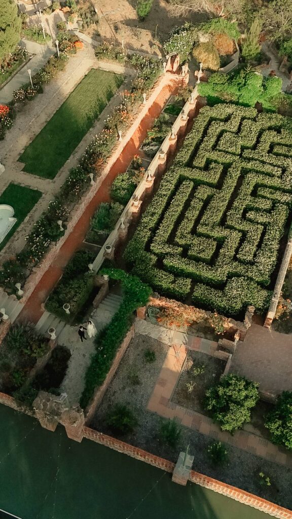 Aerial view of the hedge maze, rose garden, brick pillars, and stone pathways at Ivy Manor Temecula private estate wedding venue with bride and groom walking the grounds.