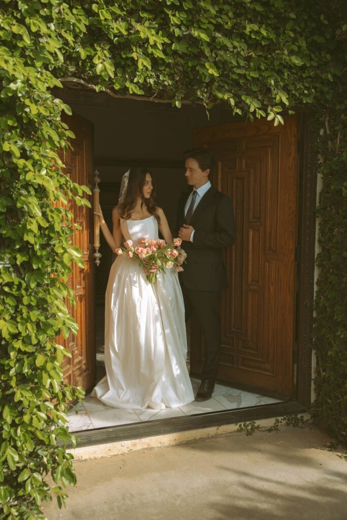 Bride and groom standing in the ivy-framed doorway of the estate mansion at a private estate wedding venue in Temecula.