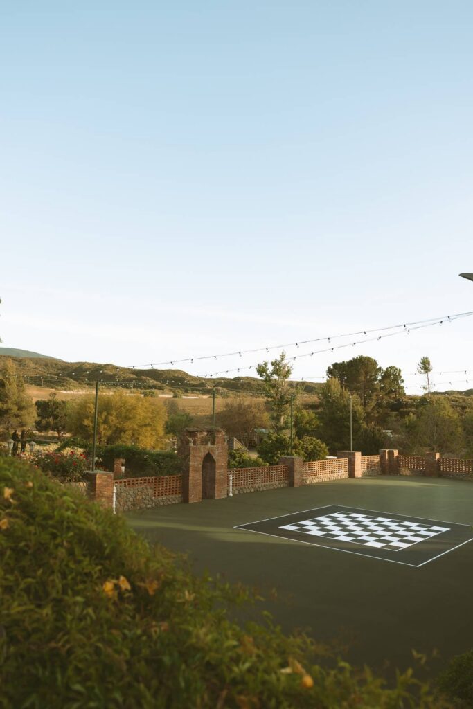 Outdoor chessboard courtyard and reception space at this private estate Temecula wedding venue, surrounded by brick walls, string lights, and wine country hillside views.