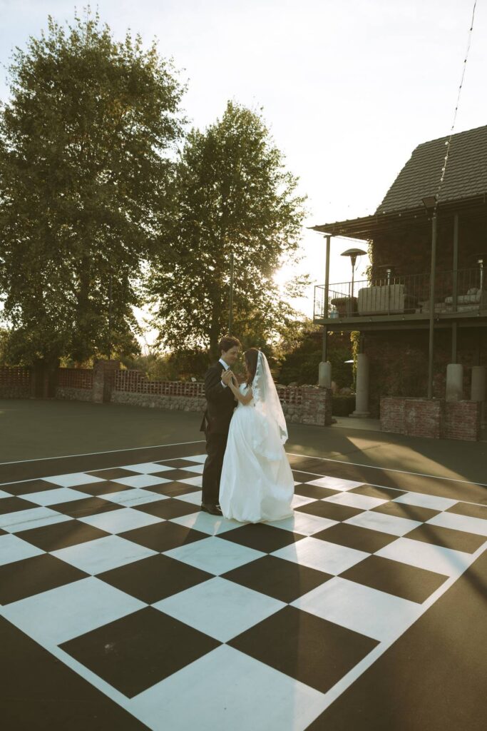Bride and groom sharing a private dance on the chessboard courtyard at golden hour at this Temecula private estate wedding venue.