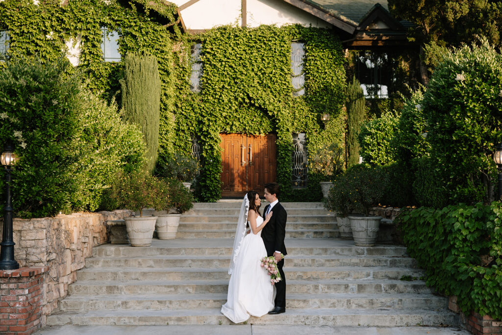 Bride and groom in front of the ivy-covered entrance to the mansion at this private estate Temecula wedding venue.